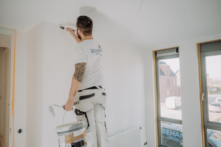 Schilder verft de bovenste rand van een muur