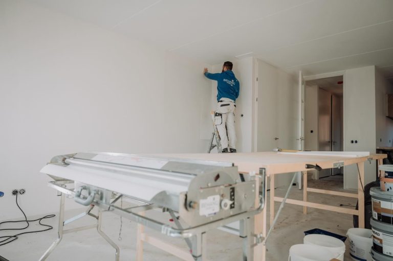 Behanger hangt behang in de hoek van een wand