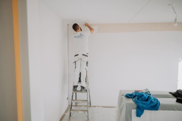 Schilder werkt de randen van een muur af op een trap