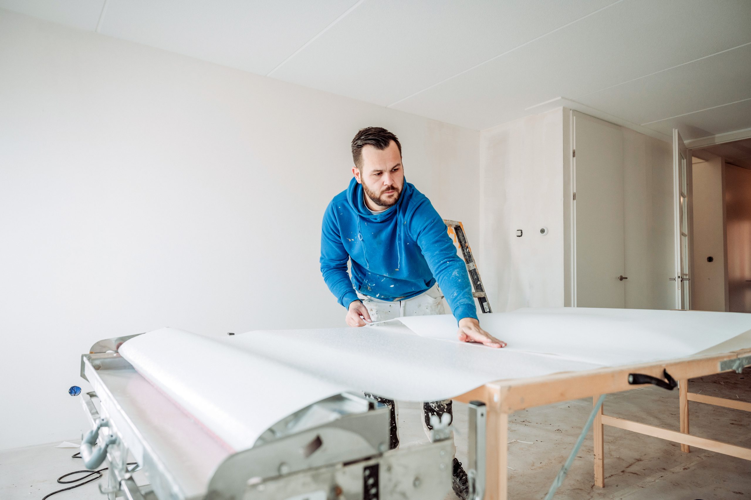 Behanger snijdt behang voor muur